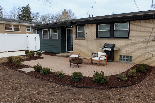 back of property featuring a fire pit, brick siding, fence, a chimney, and a patio area