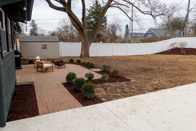 view of yard with a patio, a fenced backyard, a fire pit, a storage shed, and an outdoor structure