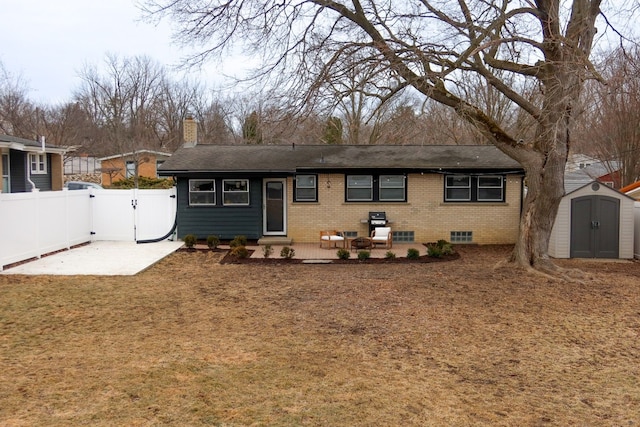 back of property featuring brick siding, a patio, a storage unit, fence, and an outdoor structure