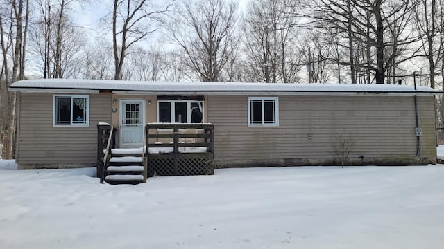 snow covered rear of property with crawl space