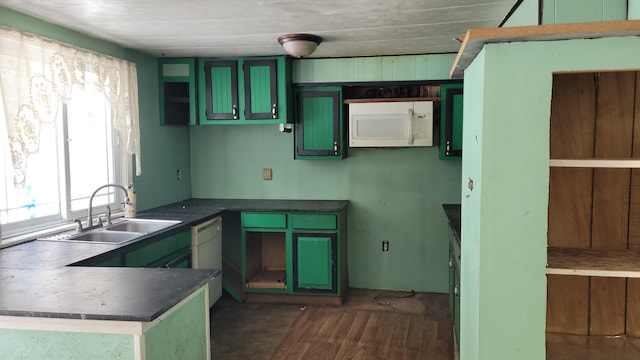 kitchen featuring white appliances, dark wood-style flooring, a sink, green cabinets, and dark countertops