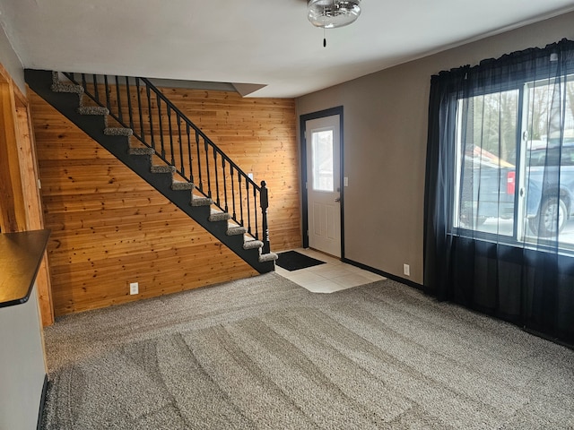 carpeted entrance foyer with stairway and wood walls