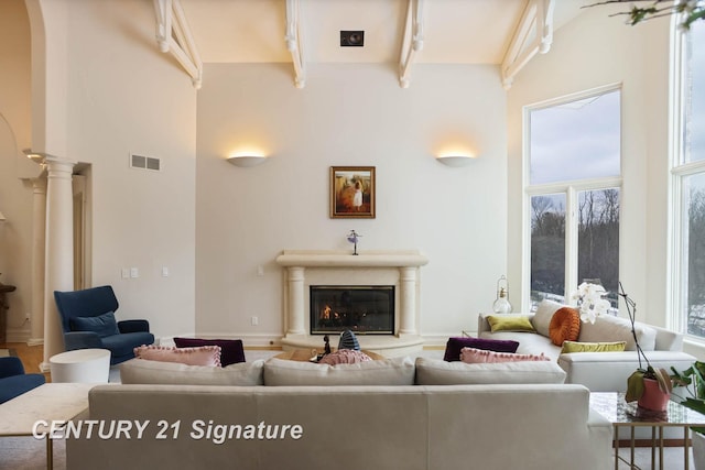 living room with arched walkways, visible vents, a high ceiling, a glass covered fireplace, and beamed ceiling