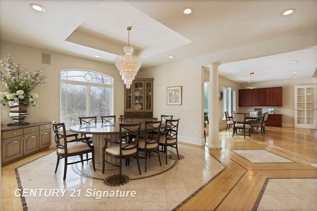 dining room featuring ornate columns, recessed lighting, a raised ceiling, and baseboards