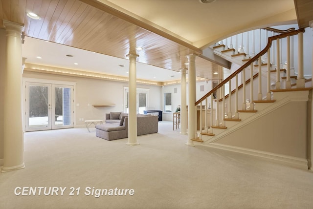 unfurnished living room featuring carpet floors, french doors, stairway, and decorative columns