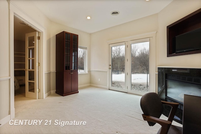 office area featuring a glass covered fireplace, carpet flooring, visible vents, and baseboards