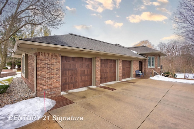 view of property exterior with a garage, a shingled roof, concrete driveway, and brick siding