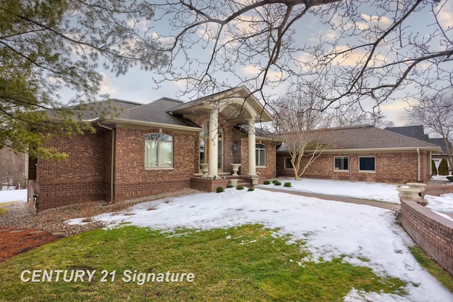 snow covered rear of property with brick siding