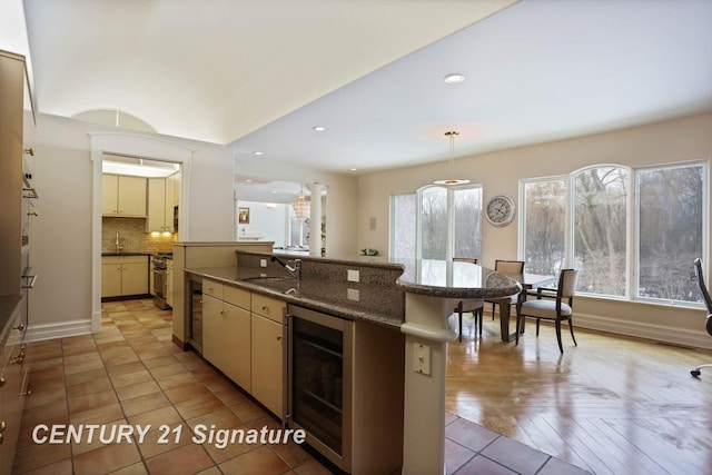 kitchen with wine cooler, pendant lighting, recessed lighting, decorative backsplash, and a sink