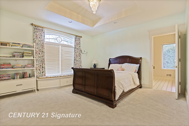 bedroom with carpet floors, a raised ceiling, and multiple windows