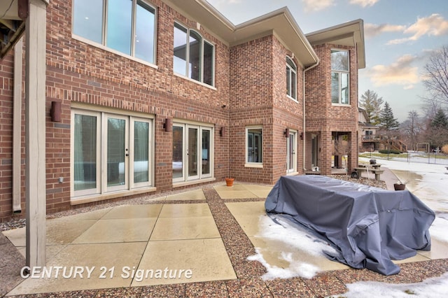 rear view of house with a patio area, french doors, and brick siding