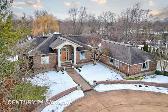 view of front of home with brick siding and roof with shingles