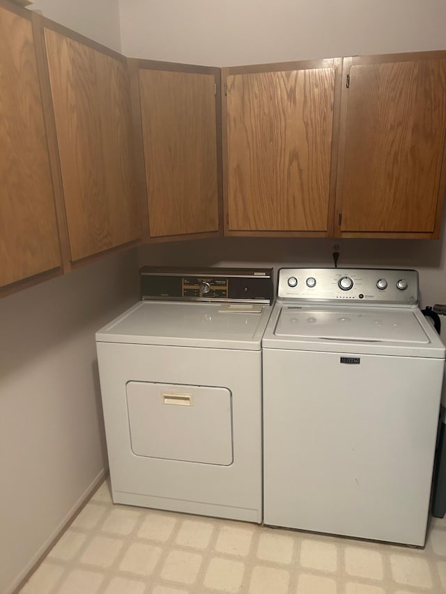 laundry room with light floors, baseboards, washer and dryer, and cabinet space