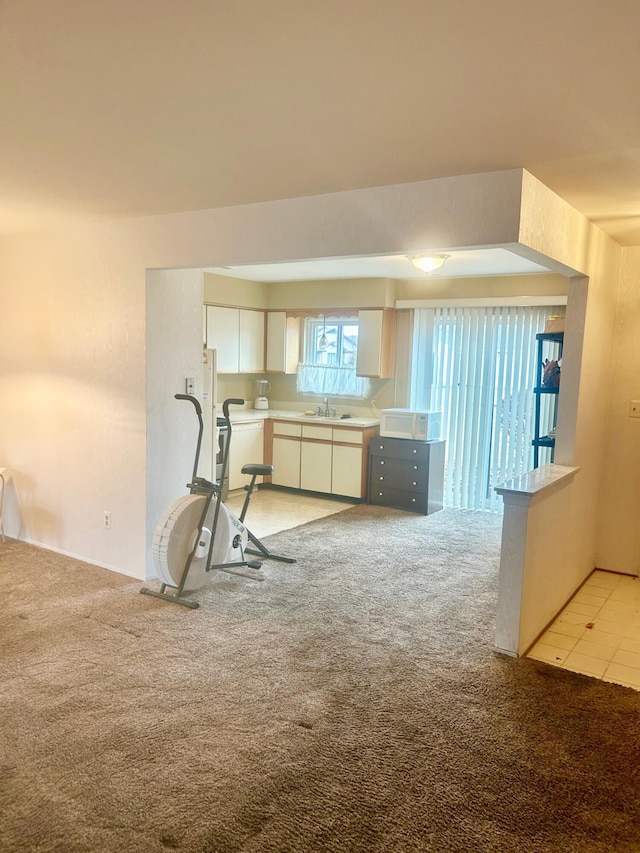 kitchen featuring light carpet, white cabinets, light countertops, and a sink