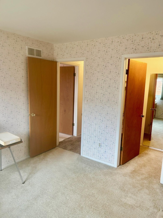 carpeted empty room with visible vents and wallpapered walls