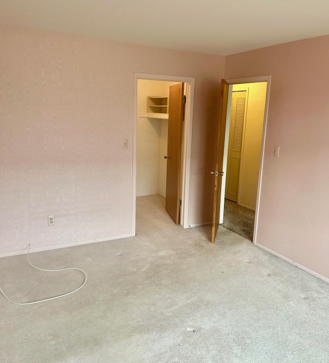 unfurnished bedroom featuring carpet floors, a walk in closet, and a closet