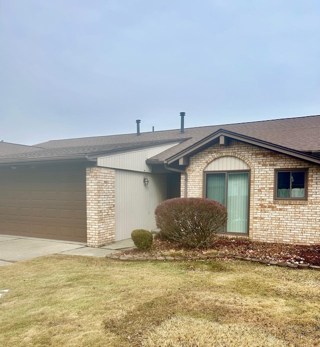 view of front of home featuring driveway, brick siding, an attached garage, and a front yard