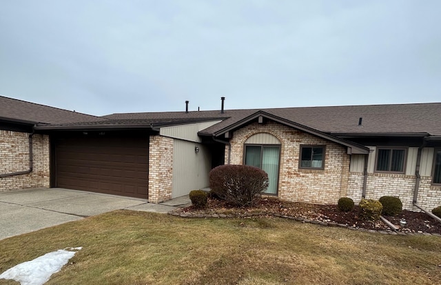 view of front facade featuring brick siding, roof with shingles, concrete driveway, a front yard, and a garage