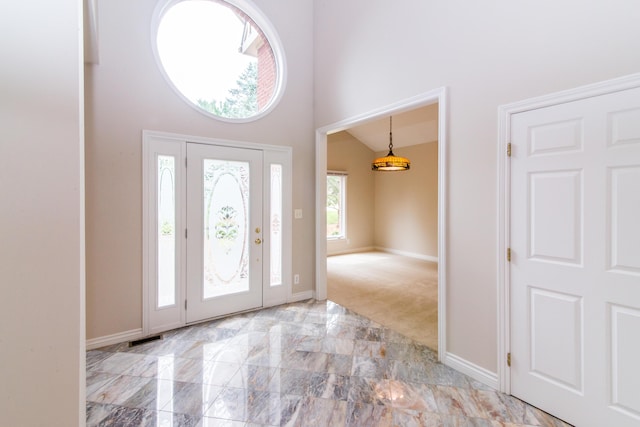 foyer entrance with marble finish floor, baseboards, visible vents, and high vaulted ceiling