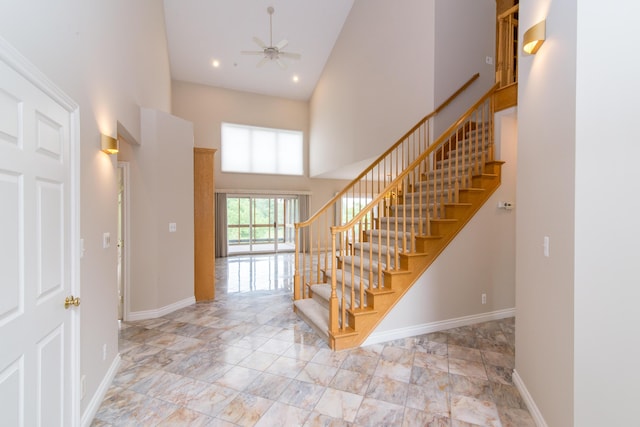 staircase with a high ceiling, recessed lighting, a ceiling fan, and baseboards