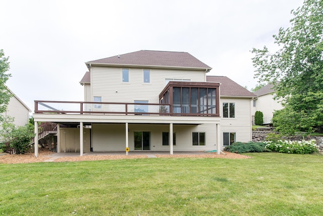 rear view of house with a sunroom, stairway, a lawn, and a wooden deck