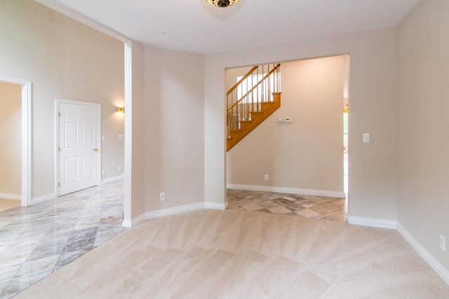 unfurnished room with light carpet, stairs, and baseboards