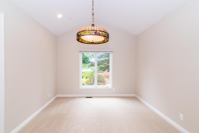 empty room featuring light colored carpet, vaulted ceiling, and baseboards