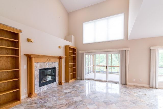 unfurnished living room featuring high vaulted ceiling, a premium fireplace, built in features, and baseboards