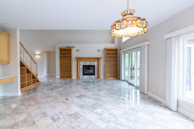 unfurnished living room featuring a premium fireplace, stairway, visible vents, and baseboards