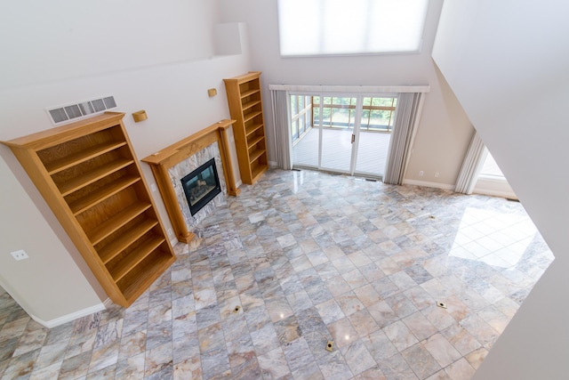 unfurnished living room featuring a high ceiling, a fireplace, visible vents, and baseboards