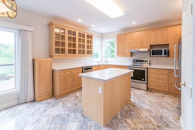 kitchen with light brown cabinets, under cabinet range hood, a sink, light countertops, and appliances with stainless steel finishes