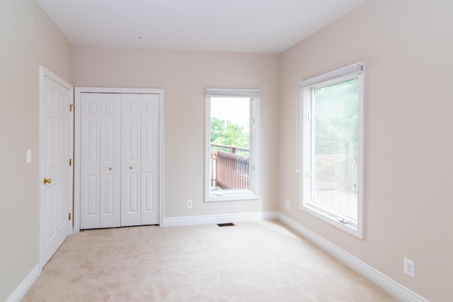 unfurnished bedroom with a closet, carpet, visible vents, and baseboards