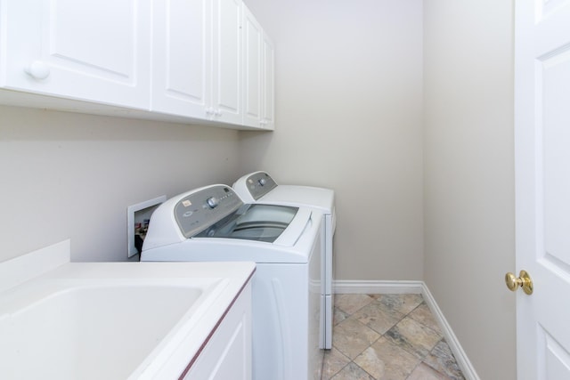 washroom with separate washer and dryer, a sink, cabinet space, and baseboards