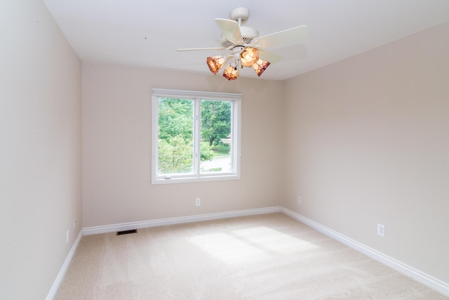 spare room featuring light carpet, baseboards, visible vents, and a ceiling fan