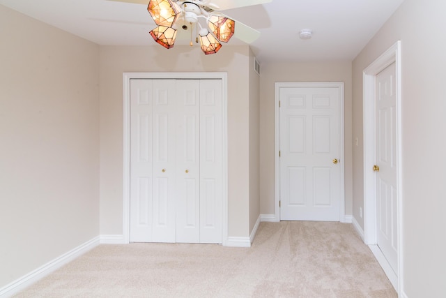 unfurnished bedroom with a closet, light carpet, and baseboards