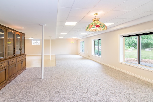 interior space with light colored carpet, a drop ceiling, and baseboards