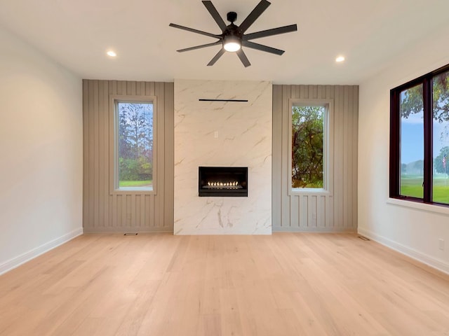 unfurnished living room with recessed lighting, a high end fireplace, ceiling fan, wood finished floors, and baseboards