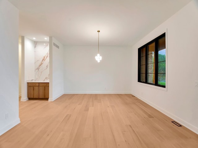 unfurnished dining area with visible vents, light wood-style flooring, and baseboards