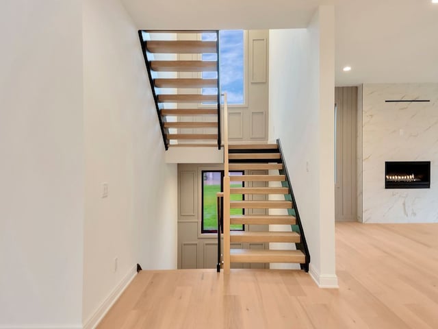 staircase with a fireplace, baseboards, wood finished floors, and recessed lighting