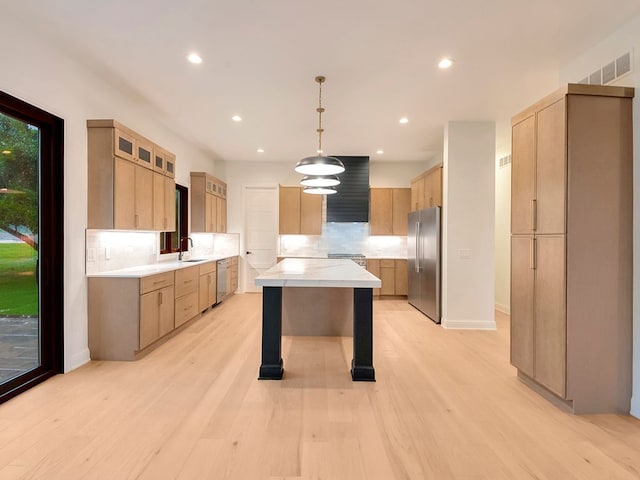 kitchen featuring a center island, tasteful backsplash, light countertops, appliances with stainless steel finishes, and a sink