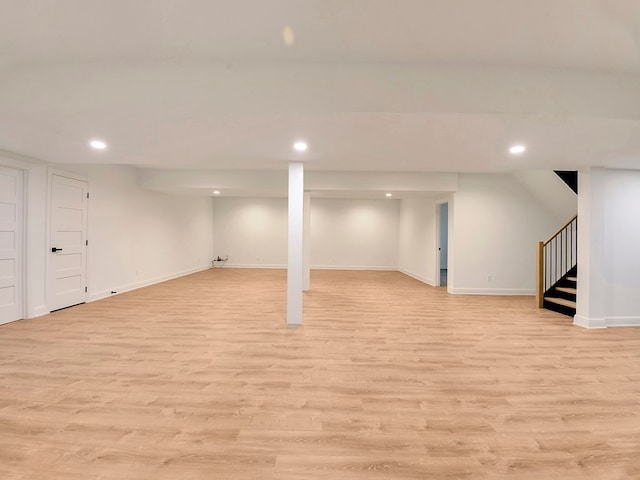 finished below grade area featuring stairs, recessed lighting, baseboards, and light wood-style floors