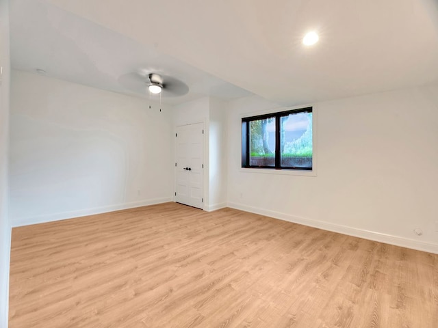 spare room featuring ceiling fan, light wood-type flooring, and baseboards