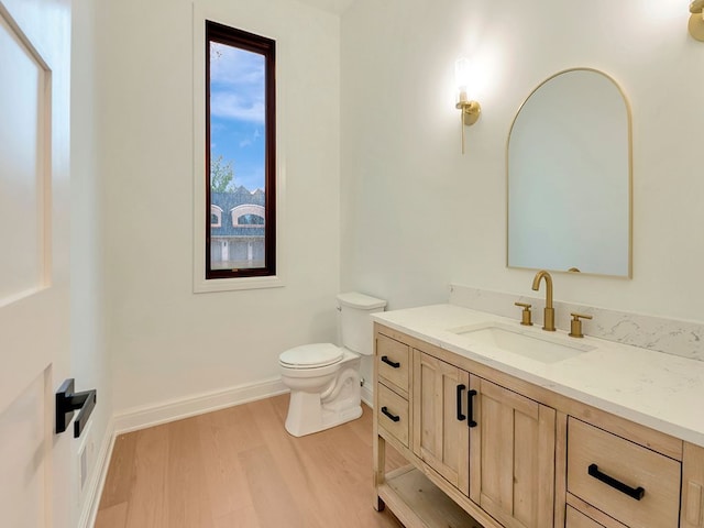 bathroom featuring baseboards, vanity, toilet, and wood finished floors