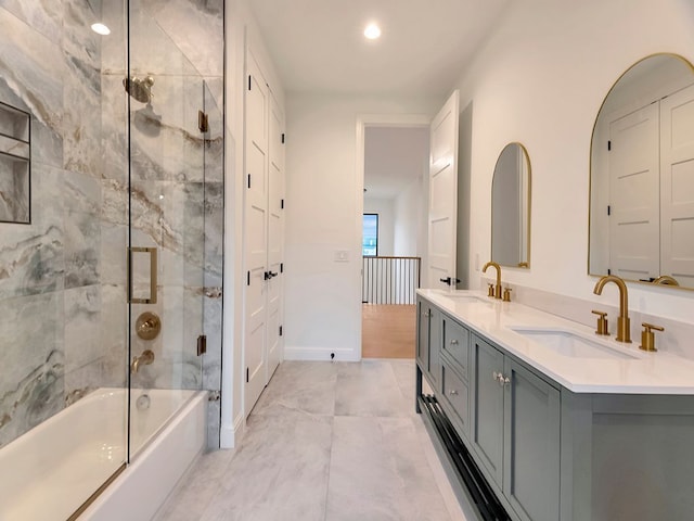 bathroom with double vanity, shower / bath combination with glass door, a sink, and baseboards