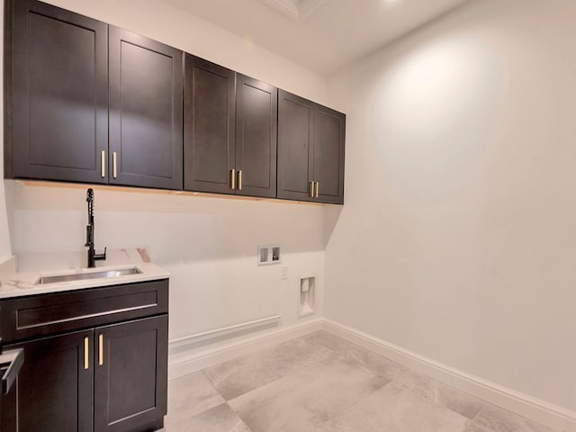 clothes washing area featuring cabinet space, hookup for a washing machine, baseboards, and a sink