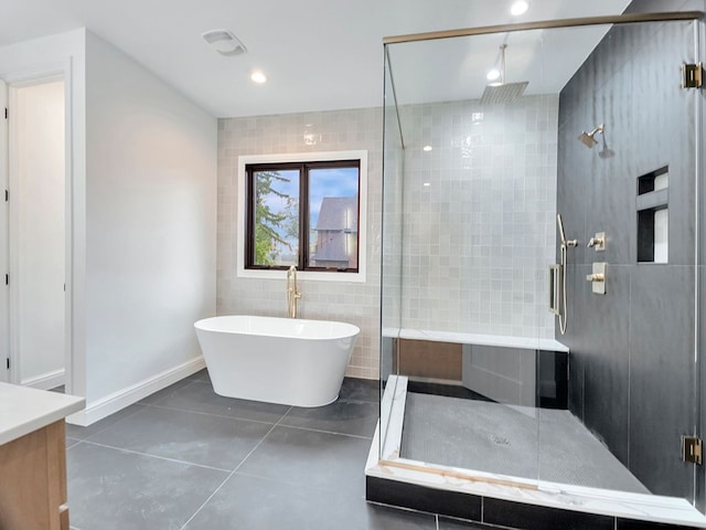 bathroom with tile patterned flooring, a freestanding tub, vanity, tile walls, and a stall shower