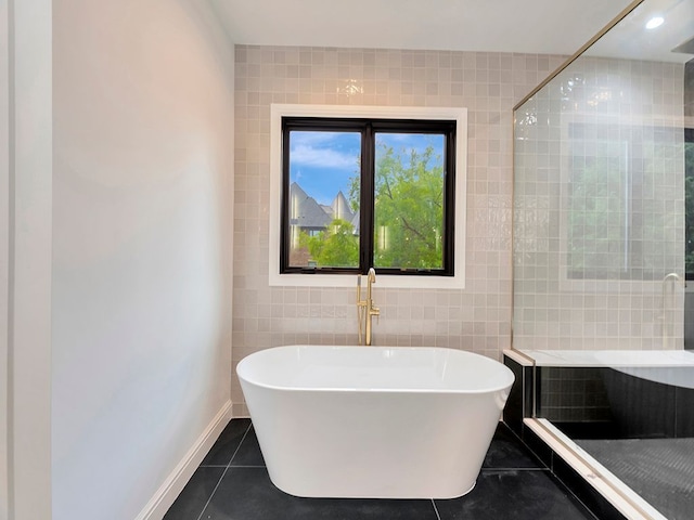 bathroom with a freestanding tub, a tile shower, tile walls, and tile patterned floors