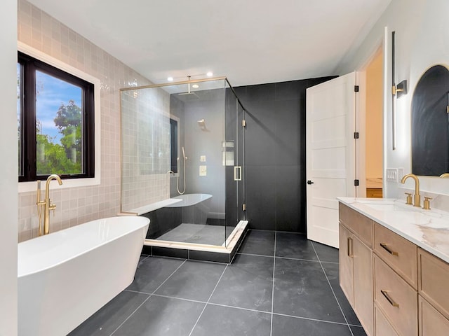 full bath featuring a freestanding tub, tile patterned flooring, vanity, tile walls, and a shower stall