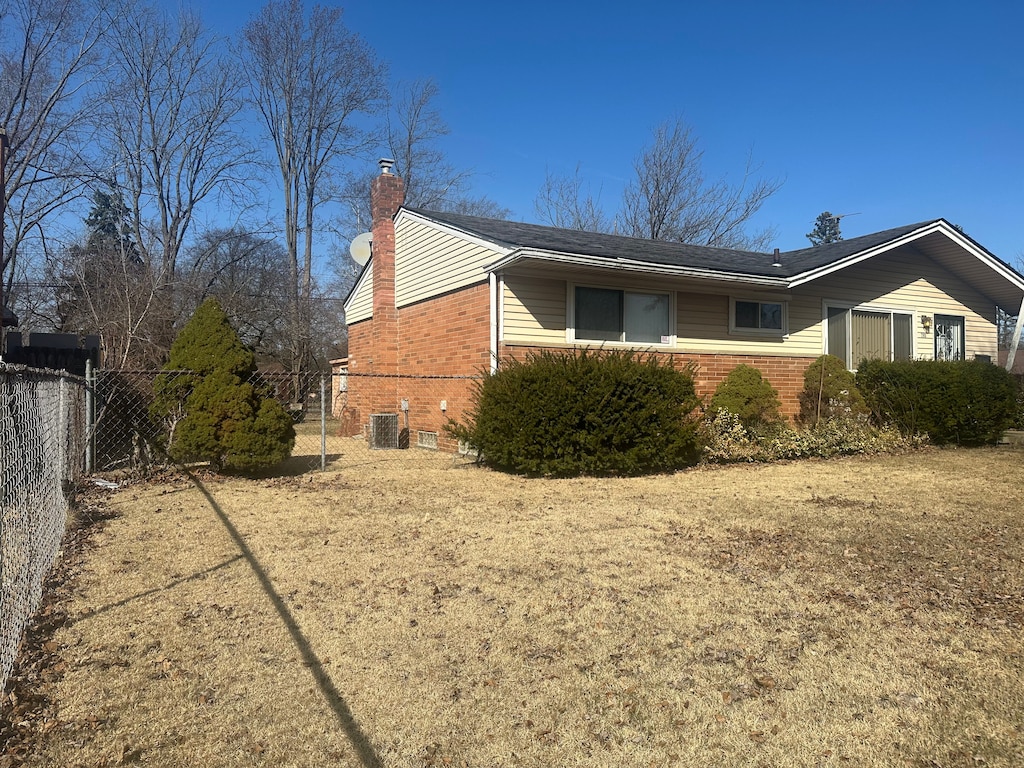 view of home's exterior with central air condition unit, fence, brick siding, and a chimney