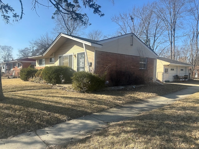 view of property exterior with a garage, brick siding, and a yard